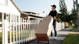 Asian man pushing cart of boxes in neighborhood