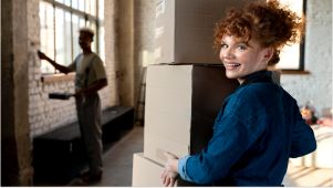 woman holding boxes and her friend painting behind her