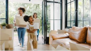 family moving into a home holding storage boxes and looking around