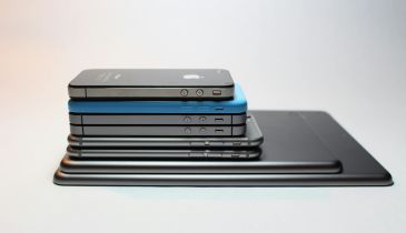 A stack of electronic devices, including various models of iPhones and iPads.