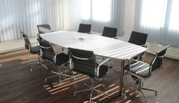 A conference room, with eight rolling chairs surrounding an empty conference table.