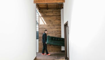 A mover carrying a sofa through a doorway.