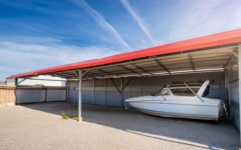 This image shows a boat under an awning at a self storage facility