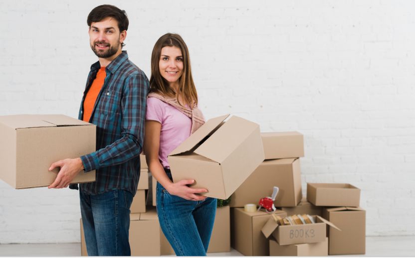 couple wearing various colors with backs together holding storage boxes
