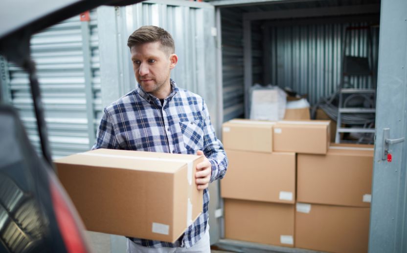 Man placing moving boxes into a business storage unit