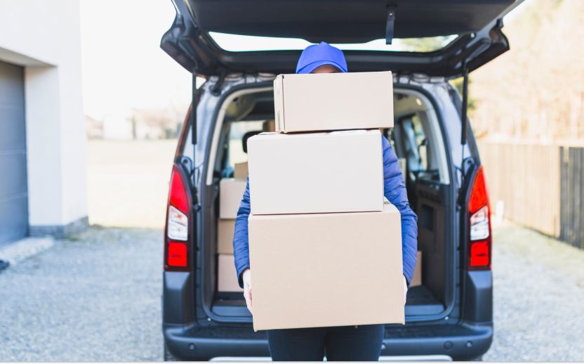 person wearing blue holding storage boxes outside an open car trunk