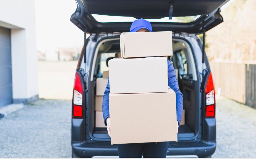 person in blue holding storage boxes vertically outside of an open car trunk