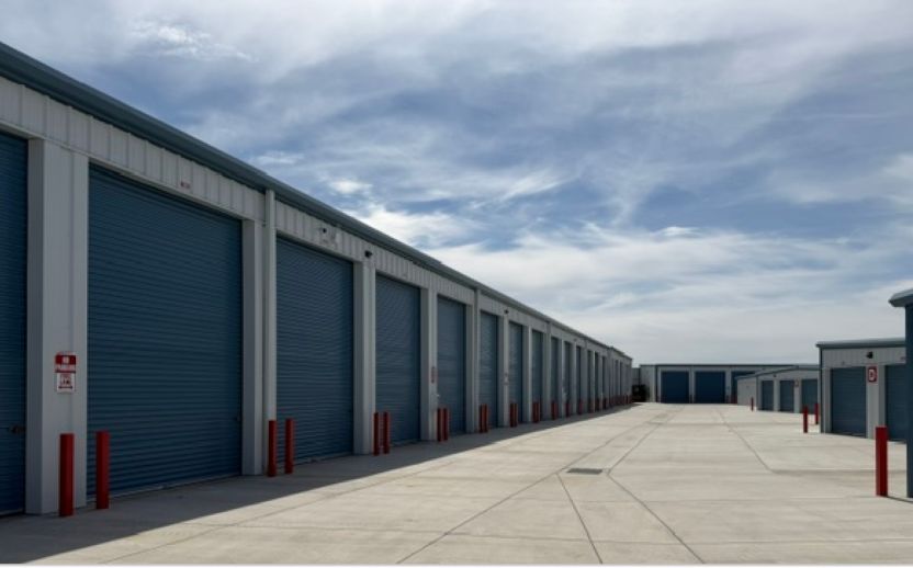 tall storage units for RV's with blue doors and a blue sky next to smaller storage units