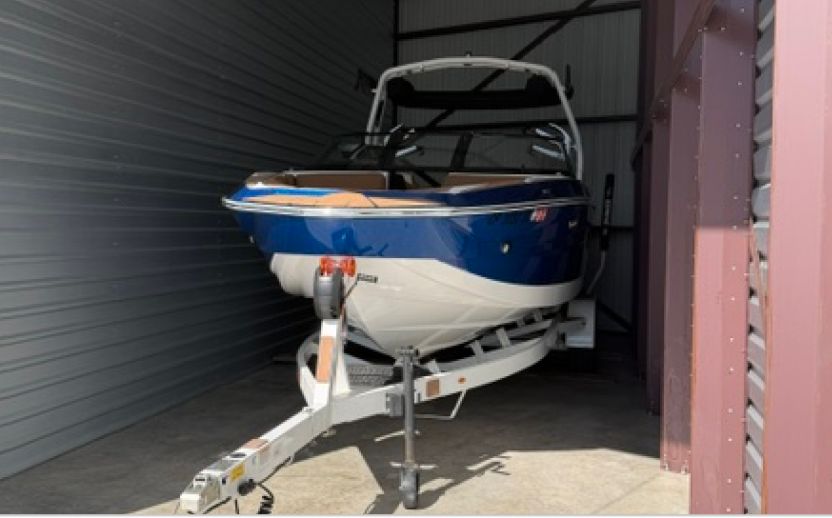 blue and white boat parked inside of a storage unit with red walls