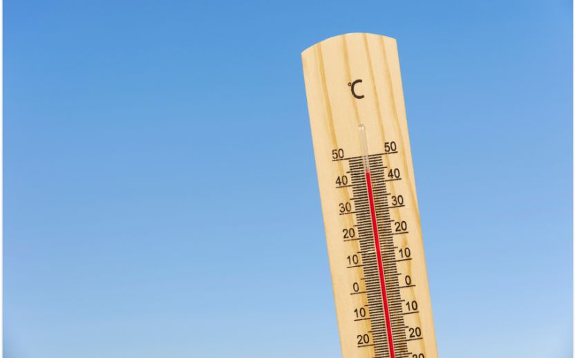 wooden thermometer outdoors with a blue sky behind