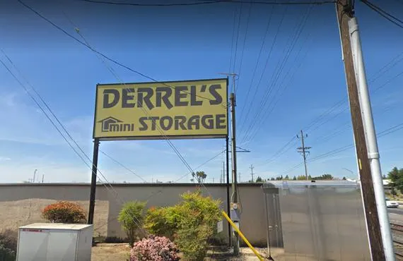 This image is of a yellow sign reading Derrel's Mini Storage at 111 S Mariposa road in Modesto California