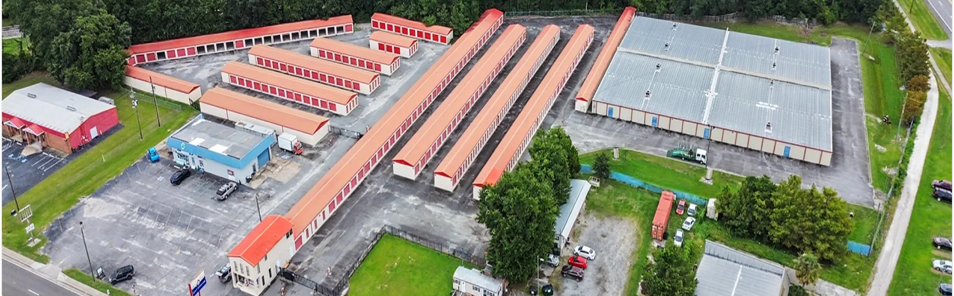 Aerial view of Stop N Stor with drive up storage units, indoor storage building, green grass and parking lots