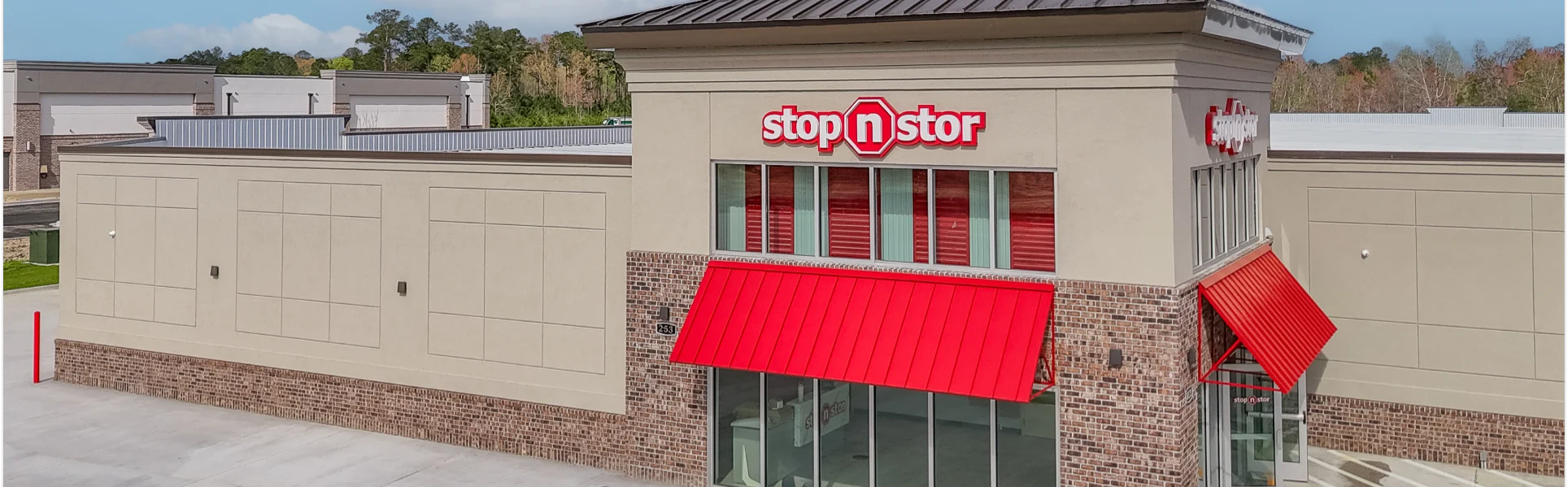 front signage of stop n stor with red umbrellas and signage
