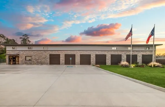 The front of Lockaway Storage. The doors to several storage units are visible behind two flagpoles holding the American and Texas state flags.