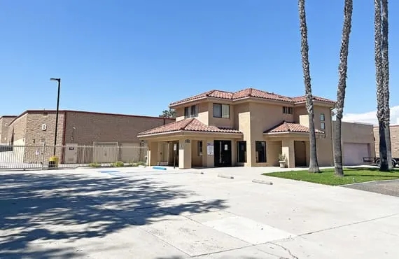The front office of the property. Next to the office is a white metal fence with a banner sign that reads 'MOVING BOXES SOLD HERE'.