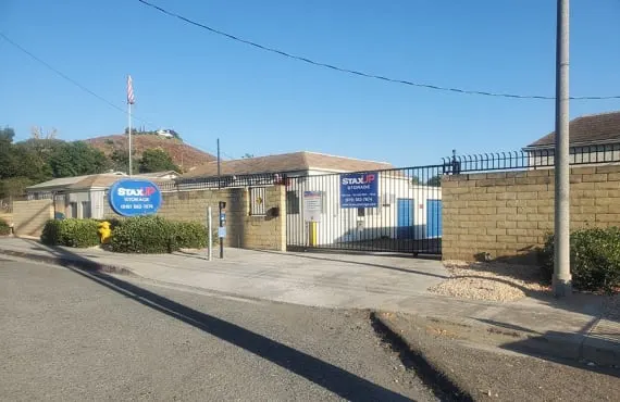 front of property with staxup storage signage on gate and a branded pole sign