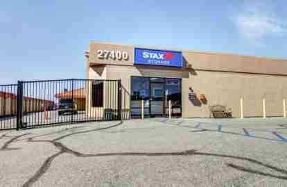 The front office of the property. The building has a StaxUP Storage sign. Next to the office is a fence and gated facility entrance.