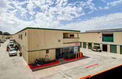 The front office of the property. The office is surrounded by drive-up storage units. Vehicles are parked in the aisles between buildings.