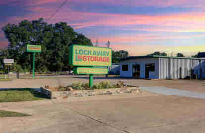 The front of the property. A Lockaway Storage sign sits in a planter with succulents. Another Lockaway Storage sign is visible in the background, as well as the front office.