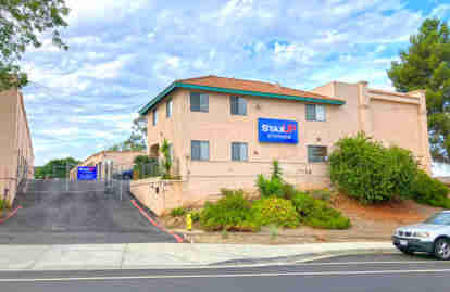 The front of the property. The front office and gate both have StaxUP Storage signs. The gate is closed.