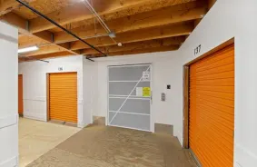 The inside of the storage facility. Orange storage unit doors line the wall.