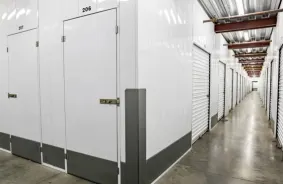 A well-lit interior hallway lined with white storage unit doors.
