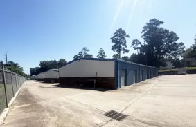 a building of drive-up storage units with the gate to the left and trees in the background