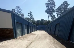 Aisle of drive-up units on either side with blue doors and trees in the background