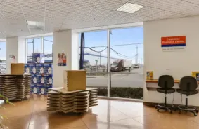 The office at A-1 Self Storage. The customer business center is visible, with two rolling chairs sitting at a desk. Stacks of cardboard boxes are available for sale.