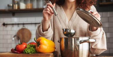 Photo of attractive caucasian woman holding cooking ladle spoon while eating soup with fresh vegetables in kitchen at home
