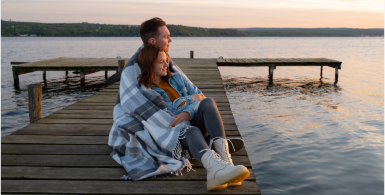 couple hugging and sitting looking at lake