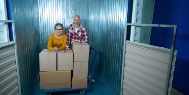 Couple standing beside stacked moving boxes inside a self-storage unit.