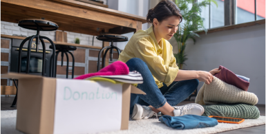 woman sitting on floow and organizing blankets into storage box