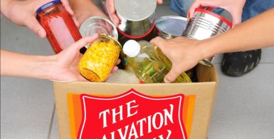 Hands putting food in a salvation army food drive bag