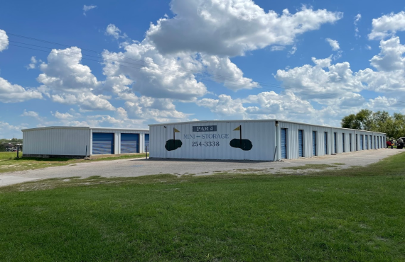 2 rows of outdoor blue and white storage units with "par 4 mini storage 254-3338" and flags printed on the wall