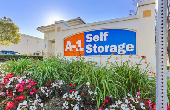 An A-1 Self Storage sign surrounded by blooming flowers.