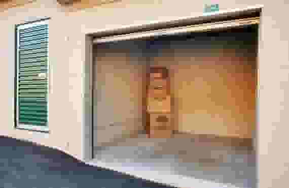 An open drive-up storage unit with a stack of cardboard boxes inside.