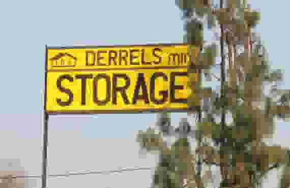 This image shows a yellow sign reading Derrel's Mini Storage