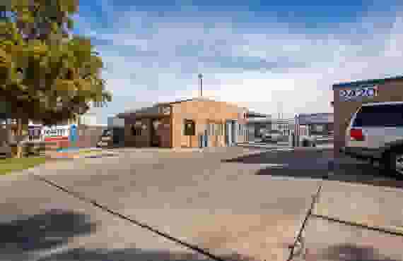 The front of the property, with the office and the gated entrance. A banner advertises trucks and trailers for rent.