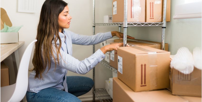 woman wearing blue crouching on floor looking at storage boxes