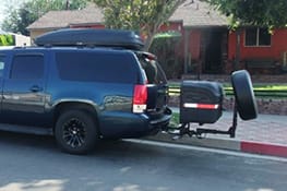 Stowaway cargo carrier on a blue SUV with tire attached