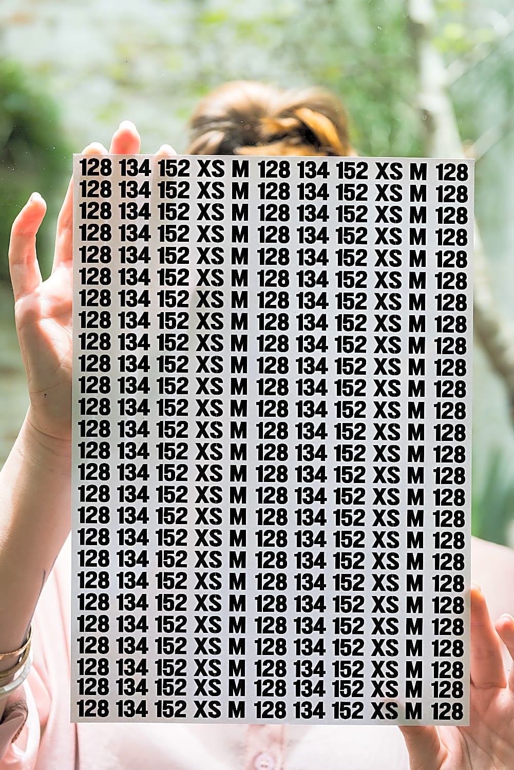 Ark med gentagne størrelsesmærker: 128, 134, 152, XS, M