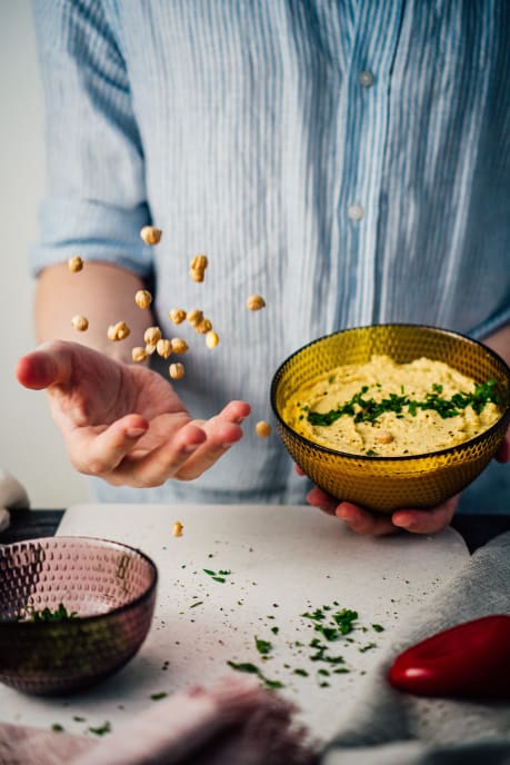 Hummus and a man throwing chick peas in the air