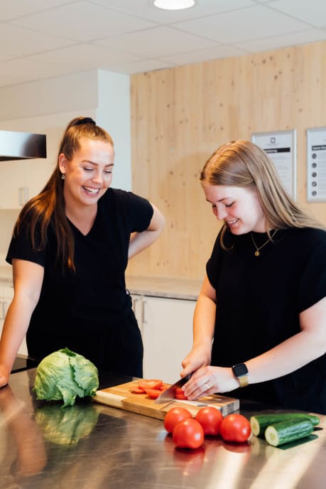 To jenter lager mat på felleskjøkken i studentbolig