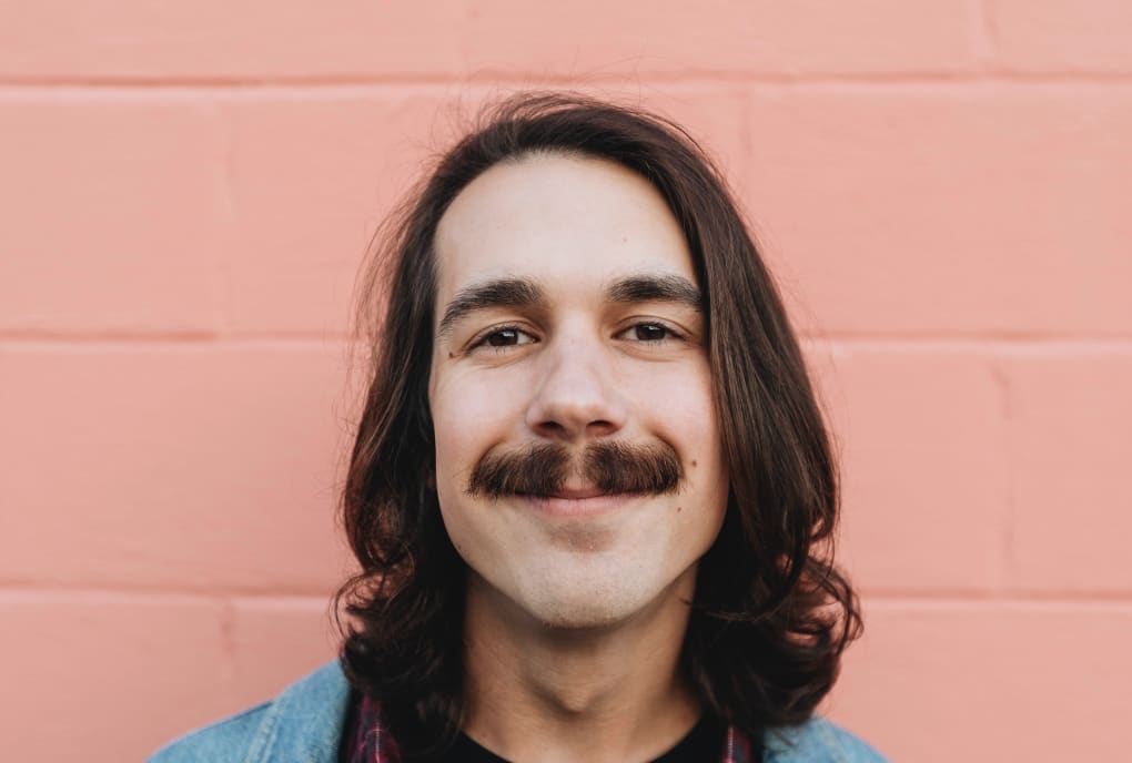 Smiling young man with long hair and a mustache