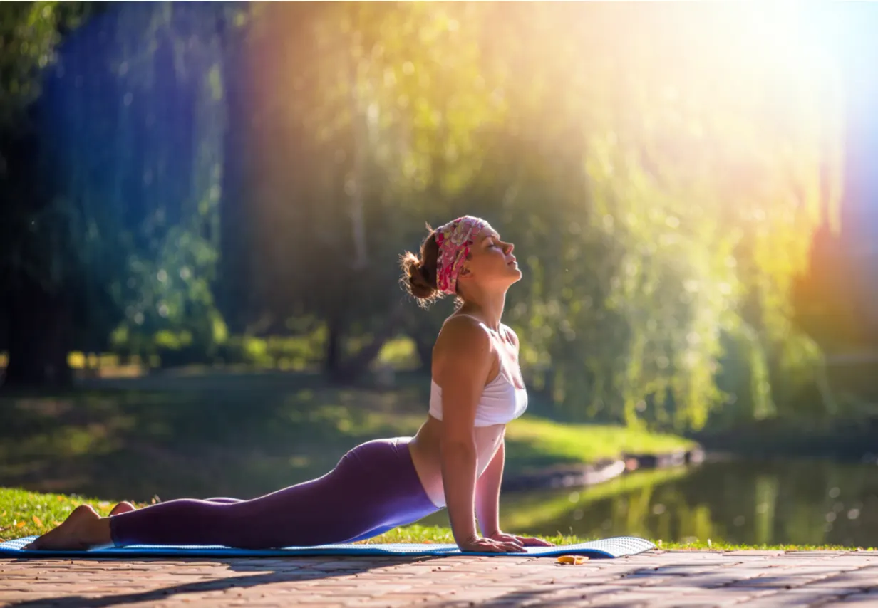 Vrouw in een yoga houding met de natuur op de achtergrond.