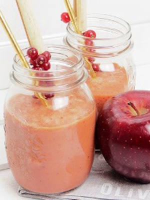 An orange smoothie in glass jars with gold straw