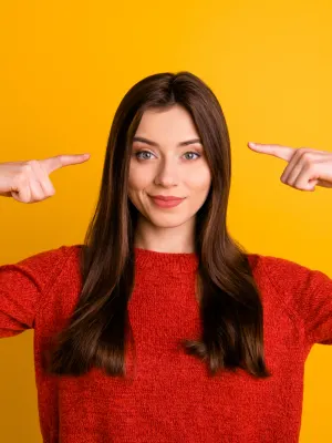 Vrouw met twee handen wijzend naar haar hoofd.