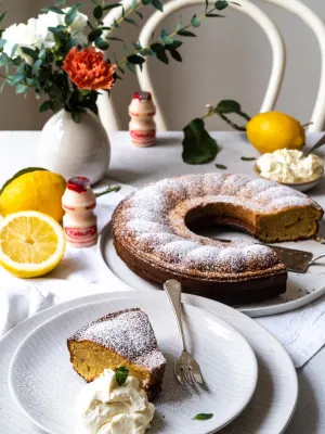 Citroen ontbijtcake met een flesje Yakult Original op een tafel met een boeket en citroenen.