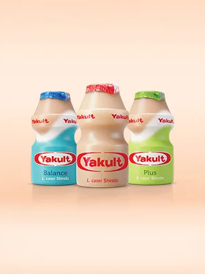 Drie flesjes Yakult Balance, Original en Plus met roze achtergrond.